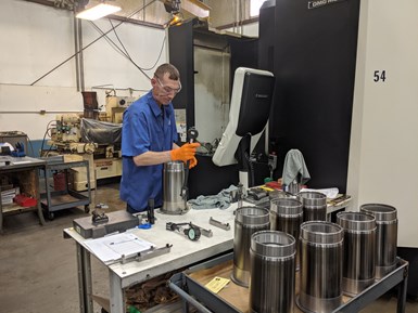 IPG employee inspecting a part next to a vertical grinding machine